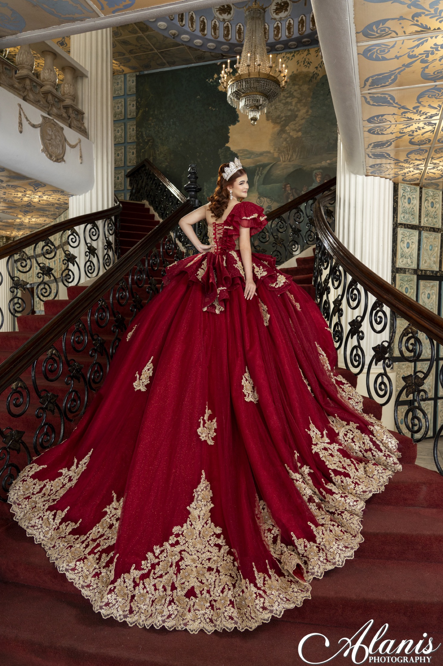 Quinceañera in a red gown on a grand staircase